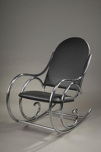 1950s rocking chair in Thonet style. It is composed of a black leatherette upholstered seat and back with oval top, above scrolling arms and undulating legs.