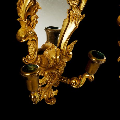 Antique twin mirrors with candlesticks in the style of Louis XV. They are made of gilded bronze. France, XIX century.
