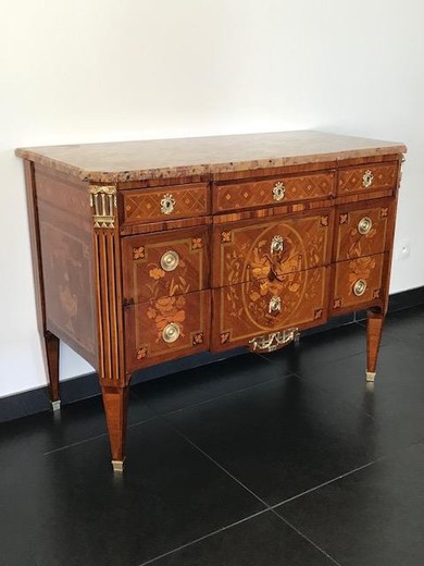 Antique chest of drawers in the style of Napoleon III. It is made of rosewood in marquetry technique. Decorated with patches of gilded bronze. The table top is marble. France, XIX century.