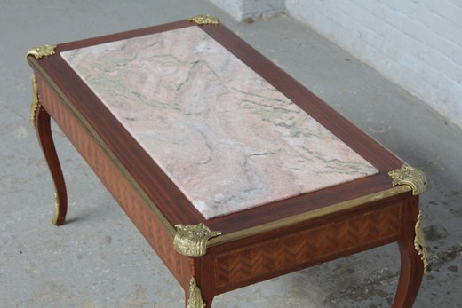 Antique coffee table in the style of Louis XV. It is made of mahogany. Decorated with patches of gilded bronze. The table top is marble. France, the 20th century.