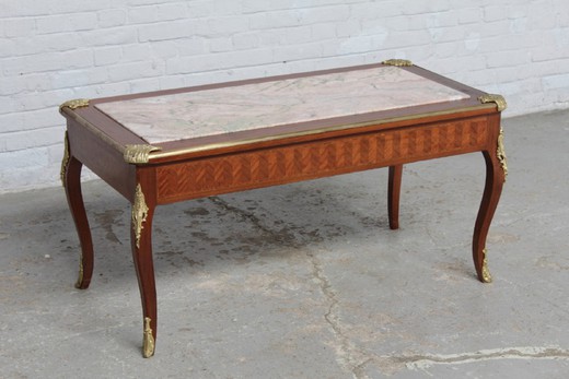 Antique coffee table in the style of Louis XV. It is made of mahogany. Decorated with patches of gilded bronze. The table top is marble. France, the 20th century.