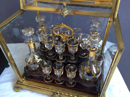 Antique liquor set of four decanters and sixteen glasses in the style of Napoleon III. The case is made of gilded bronze and crystal glass. Europe, the XIX century.