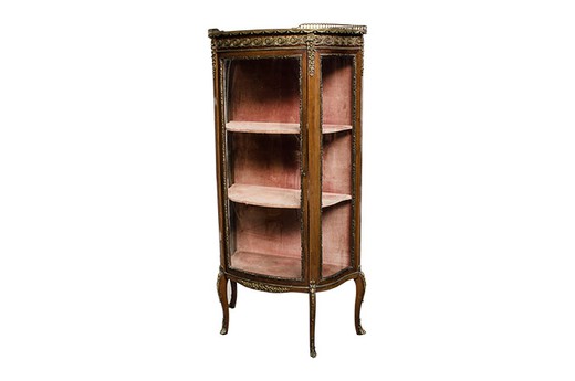 Antique showcase in the style of Louis XVI. It is made of walnut. Decorated with patches of gilded bronze. Europe, the 1880s.