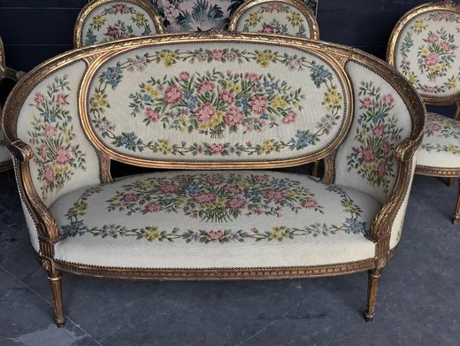 Antique set in the style of Louis XVI. The set includes a sofa and four armchairs. It is made of wood with gilding. France, XIX century.