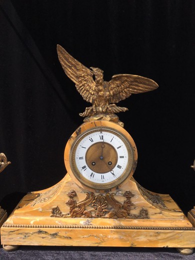 Antique clock and pair decorations in the style of Empire. They are made of marble and gilded bronze. France, XIX century.