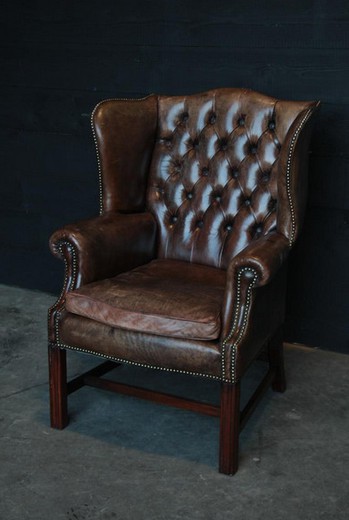 старинное кресло из кожи с оттоманкой