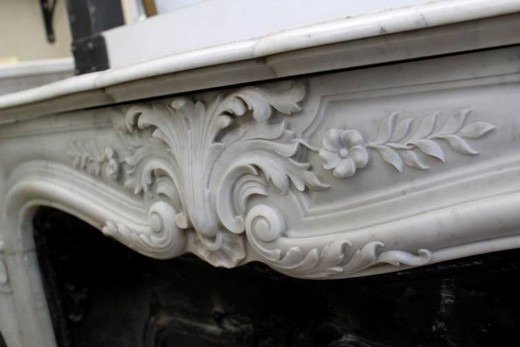 Красивый старый каминный портал в стиле Людовик XV. Выполнен из белого каррарского мрамора с классической резьбой в виде растительного орнамента, вставка из чугуна. Купить в Москве.
